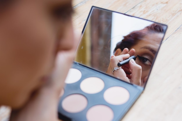 reflectie in de spiegel op de tafel van een vrouwelijk gezicht dat buitenshuis make-up opdoet