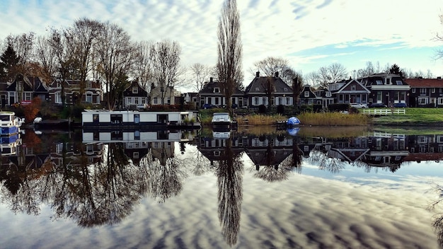 Foto reflectie van bomen en huizen in het kanaal tegen een bewolkte lucht