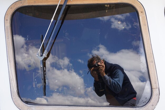 Foto reflectie van de mens op het glazen raam tegen de hemel