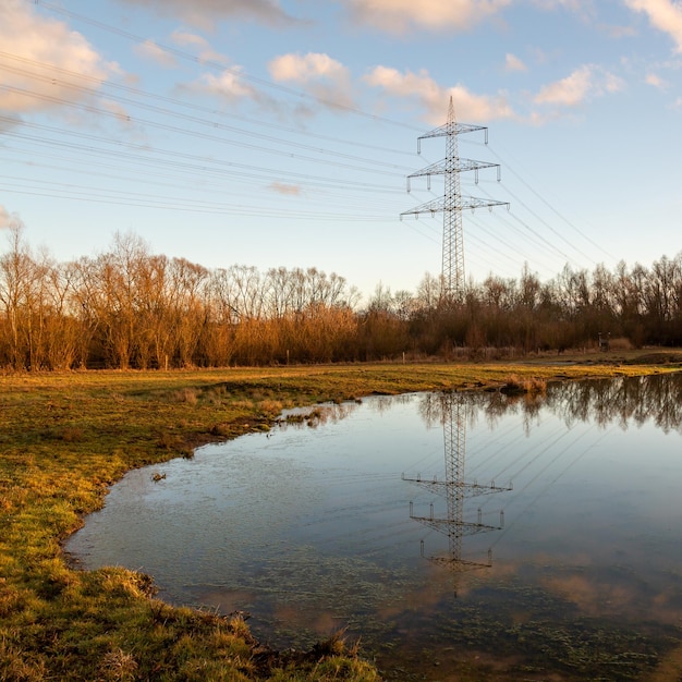 Reflectie van een elektriciteitspylon op het meer in de herfst