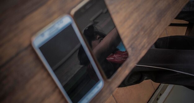 Foto reflectie van een man gezien in mobiele telefoonschermen op tafel