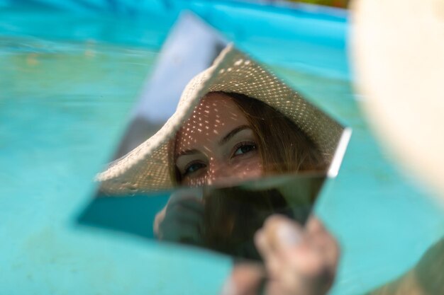 Foto reflectie van een vrouw in de spiegel terwijl ze in het zwembad zit