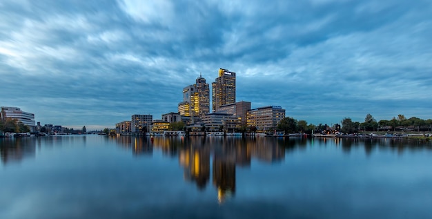 Reflectie van gebouwen op het meer tegen een bewolkte hemel in de schemering