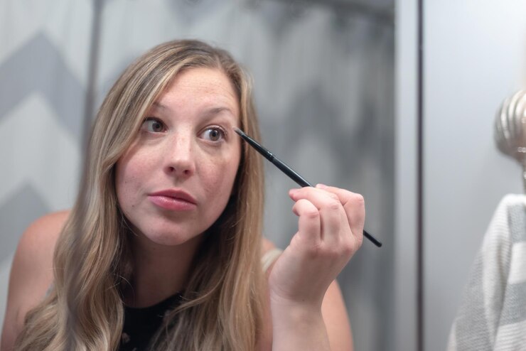 Foto reflectie van glimlachende jonge vrouw die make-up aanbrengt in de spiegel