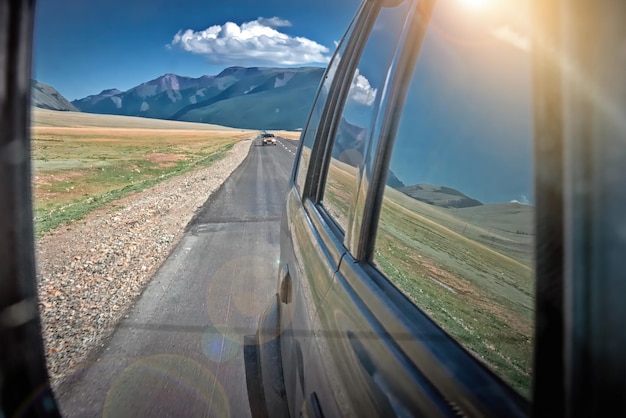 Foto reflectie van het berglandschap in de achteruitkijkspiegel van een auto