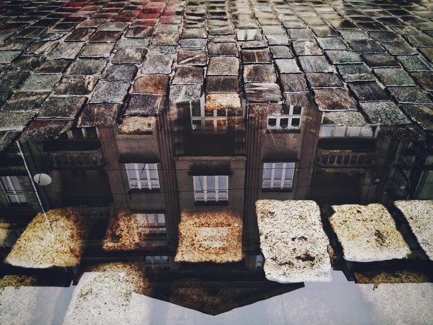 Foto reflectie van het gebouw in de plas op geplaveide steen