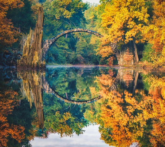 reflection of arch and trees in lake