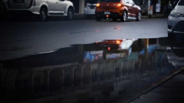 激しい雨が降った後、街の通りの水たまりにぼやけた車の反射、選択的な焦点。梅雨、交通機関の背景。