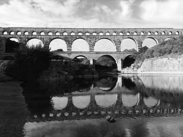 Photo reflection of bridge on water against sky