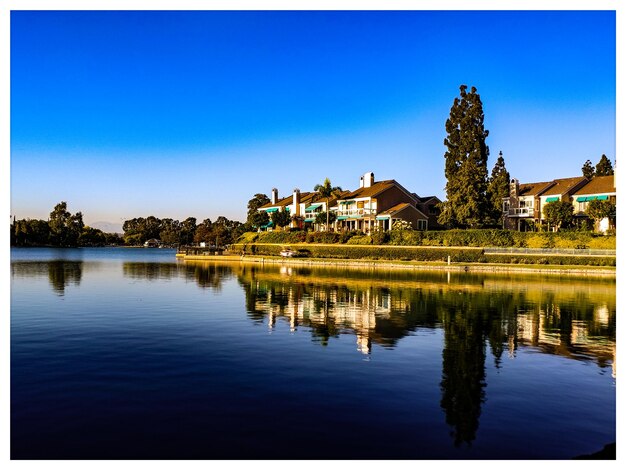 Reflection of building in lake against clear blue sky