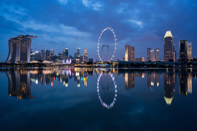 Foto riflessione di edifici e ruota panoramica nel fiume di notte