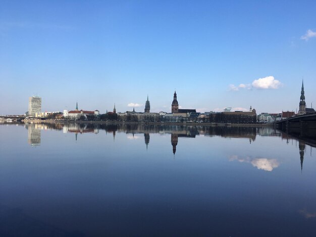 Reflection of buildings in lake against blue sky