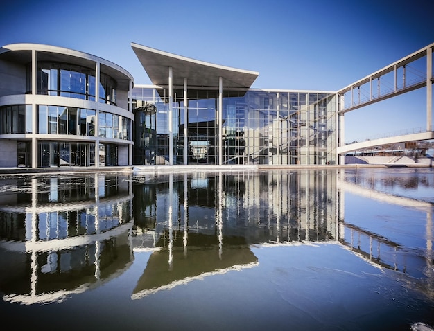 Reflection of buildings in lake against blue sky