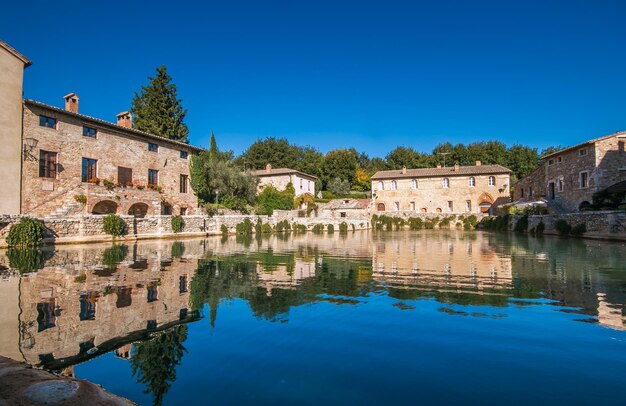 Reflection of buildings in lake against clear blue sky bagno vigoni italy