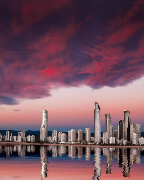 Photo reflection of buildings in sea against sky during sunset