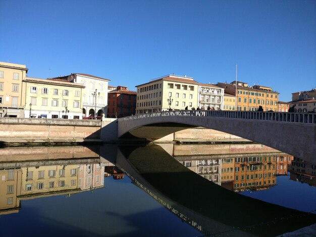 Reflection of buildings in water against clear sky