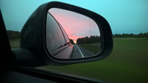Photo reflection of car on road in side-view mirror