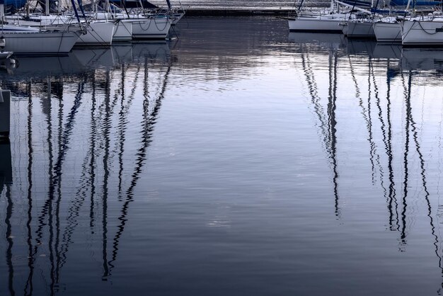 イタリアのガルダ湖の沖合に係留された夕方の空とヨットのマストの反射