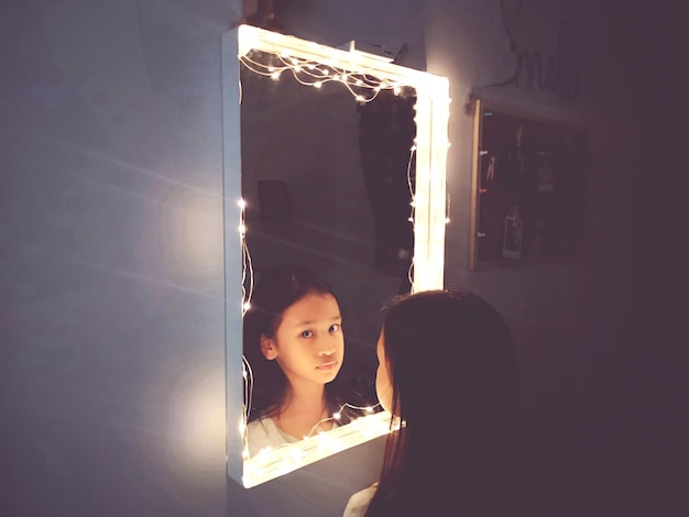 Photo reflection of girl in illuminated mirror at home