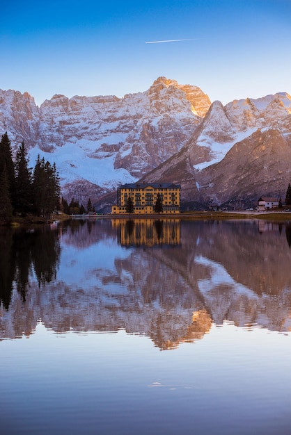 Reflection of house in lake against snowcapped mountain