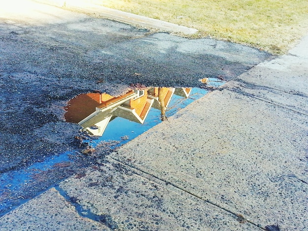 Reflection of house in puddle on road