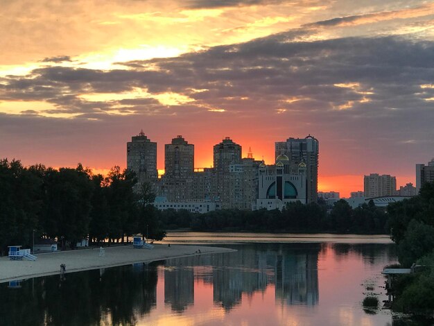 Reflection of illuminated buildings against sky at sunset