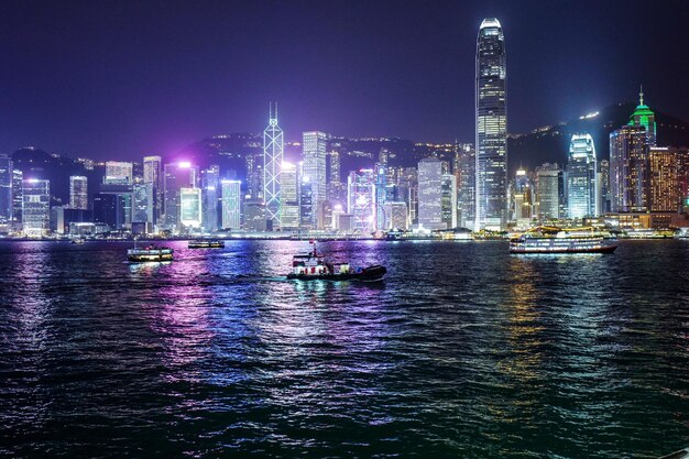 Reflection of illuminated city in river against sky