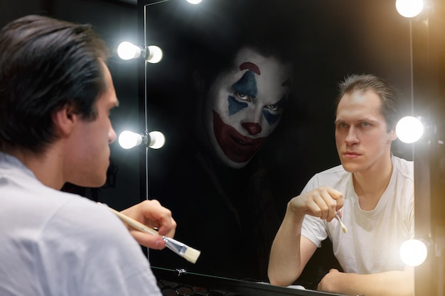 Foto riflesso di un uomo che tiene in mano un pennello da trucco