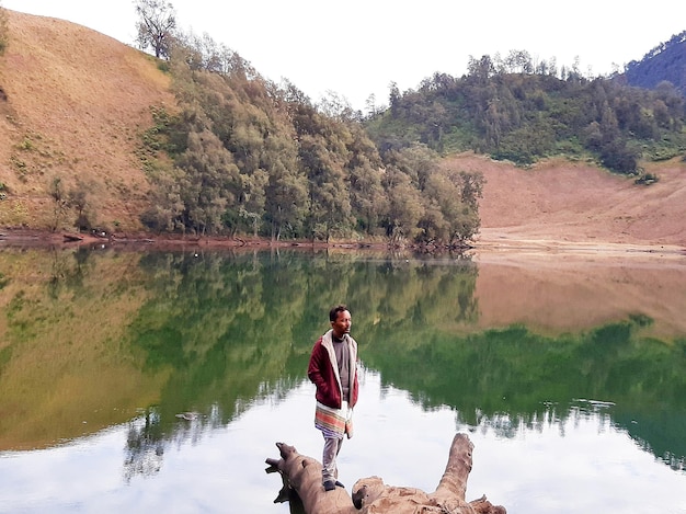 Photo reflection of man in lake against trees on mountain