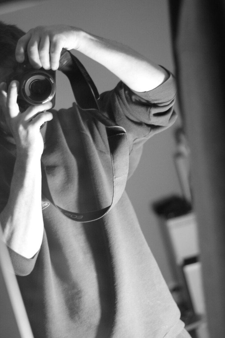 Photo reflection of man photographing with camera on mirror