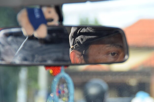 Photo reflection of man in rear-view mirror