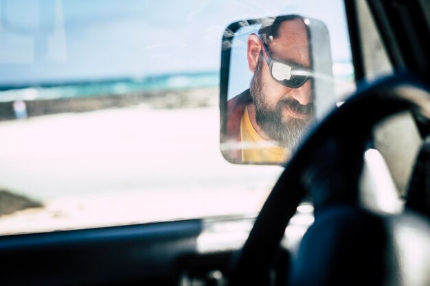 Foto riflesso dell'uomo visto nello specchio laterale di un'auto