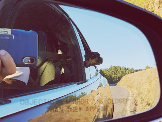 Reflection of man on side-view mirror of car