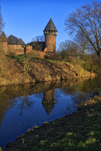 Reflection of moated castel in pond against sky