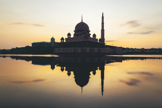 The reflection of the mosque is seen in the water.