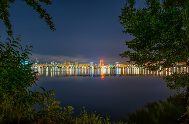 Reflection of the night city in a wide calm river.