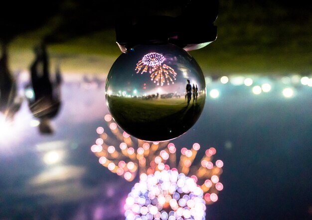 写真 夜フィールドのクリスタルボールに反射する花火