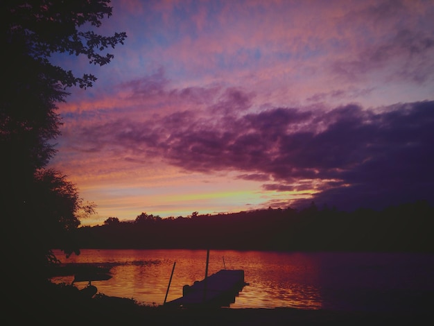 写真 夕暮れの静かな湖に映る木のシルエット