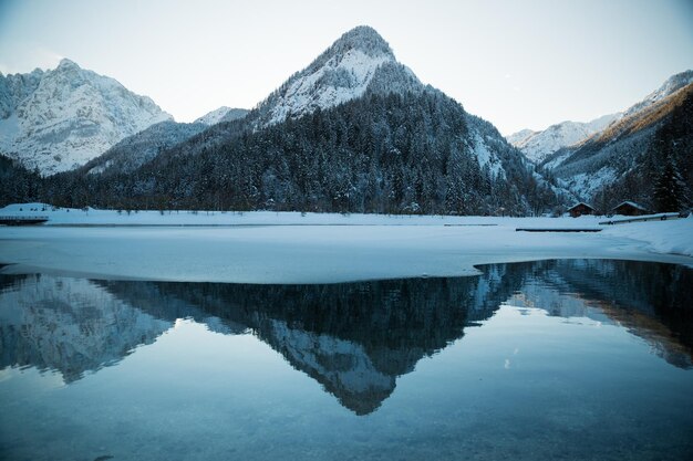 写真 空に照らされた湖の雪に覆われた山の反射