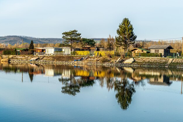 写真 空に照らされた湖の木や建物の反射