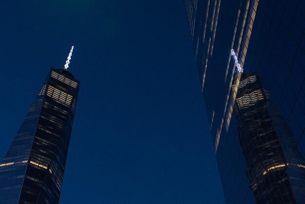 Reflection of the One World Trade Center building on the facade of another nearby building at night