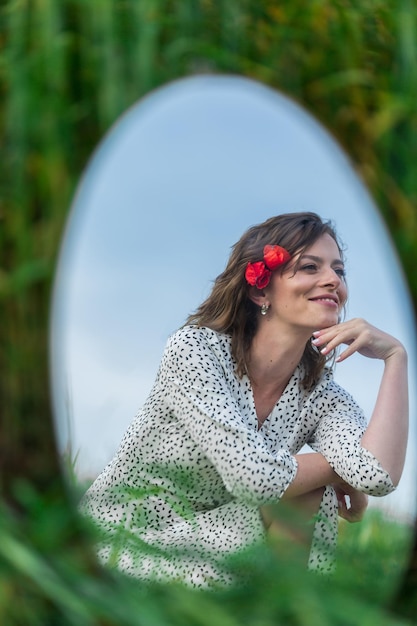 Reflection in the oval mirror of an attractive brunette with curly hair and cute smile