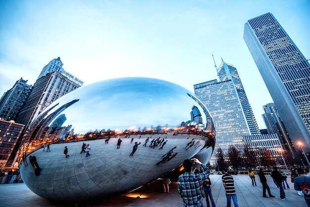 Foto riflessione di persone e edifici moderni sulla scultura contro il cielo