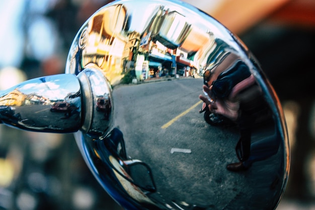 Photo reflection of person photographing with camera on side-view mirror of vehicle