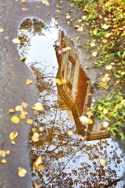 Photo reflection in a puddle of an old house in autumn