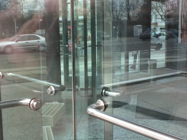 Foto riflessione della strada e dell'auto sulla porta di vetro