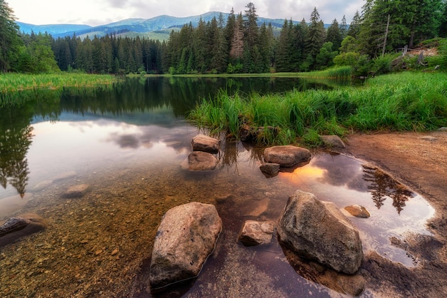 Reflection of trees and colorful sky in lake Vrbicke pleso Slovakia