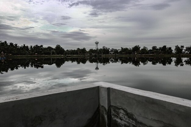 Reflection of trees in swimming pool against sky