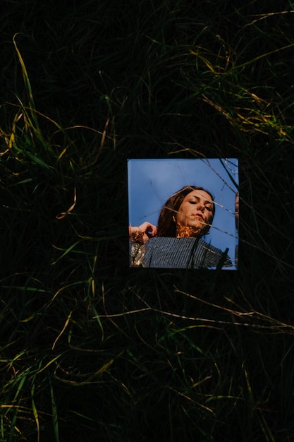 Photo reflection of woman on mirror amidst grass