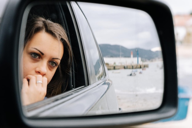 Photo reflection of woman on side view mirror of car